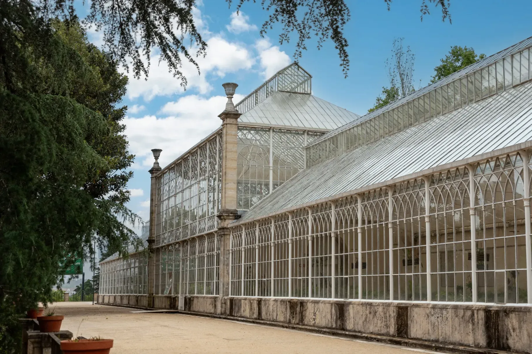 The historic 19th-century iron and glass greenhouse at the University of Coimbra Botanic Garden, one of the oldest in Europe.